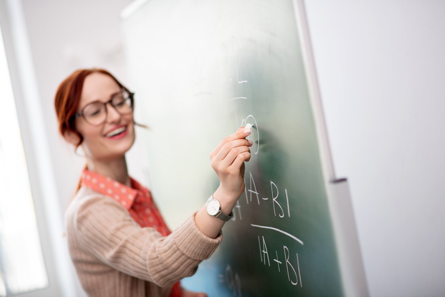 Answer holding. Учитель в очках. преподаватель в очках. a female teacher holding a fallen chalk on the floor.