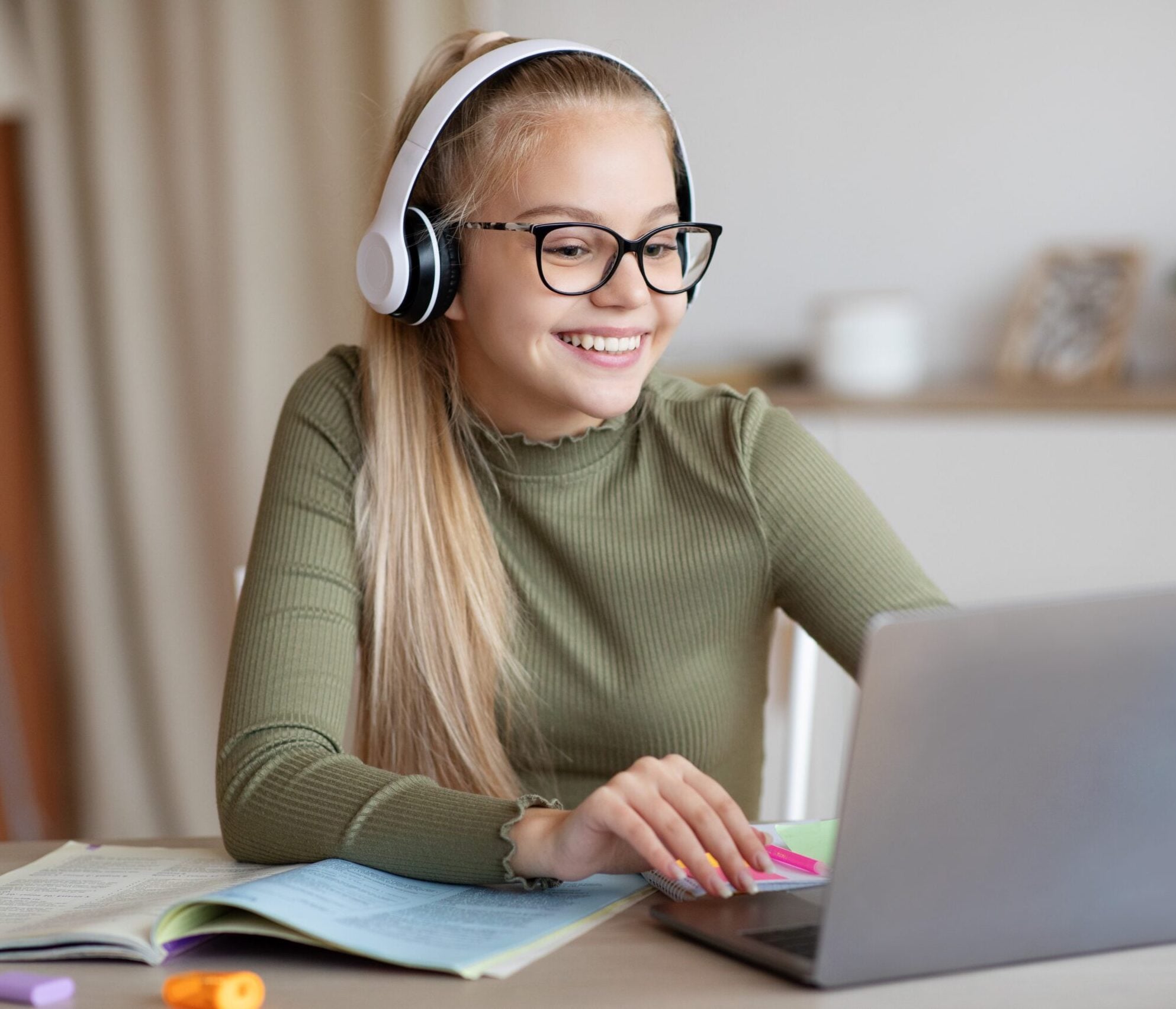 Jeune élève secondaire heureuse participant à un cours d'été Tutorax en ligne avec un tuteur via son ordinateur portable.